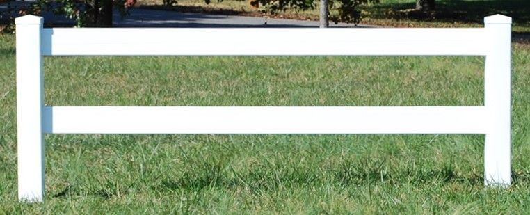 A white fence is sitting in the middle of a lush green field.