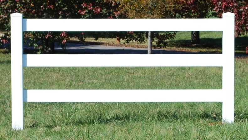 A white fence is sitting in the middle of a grassy field.