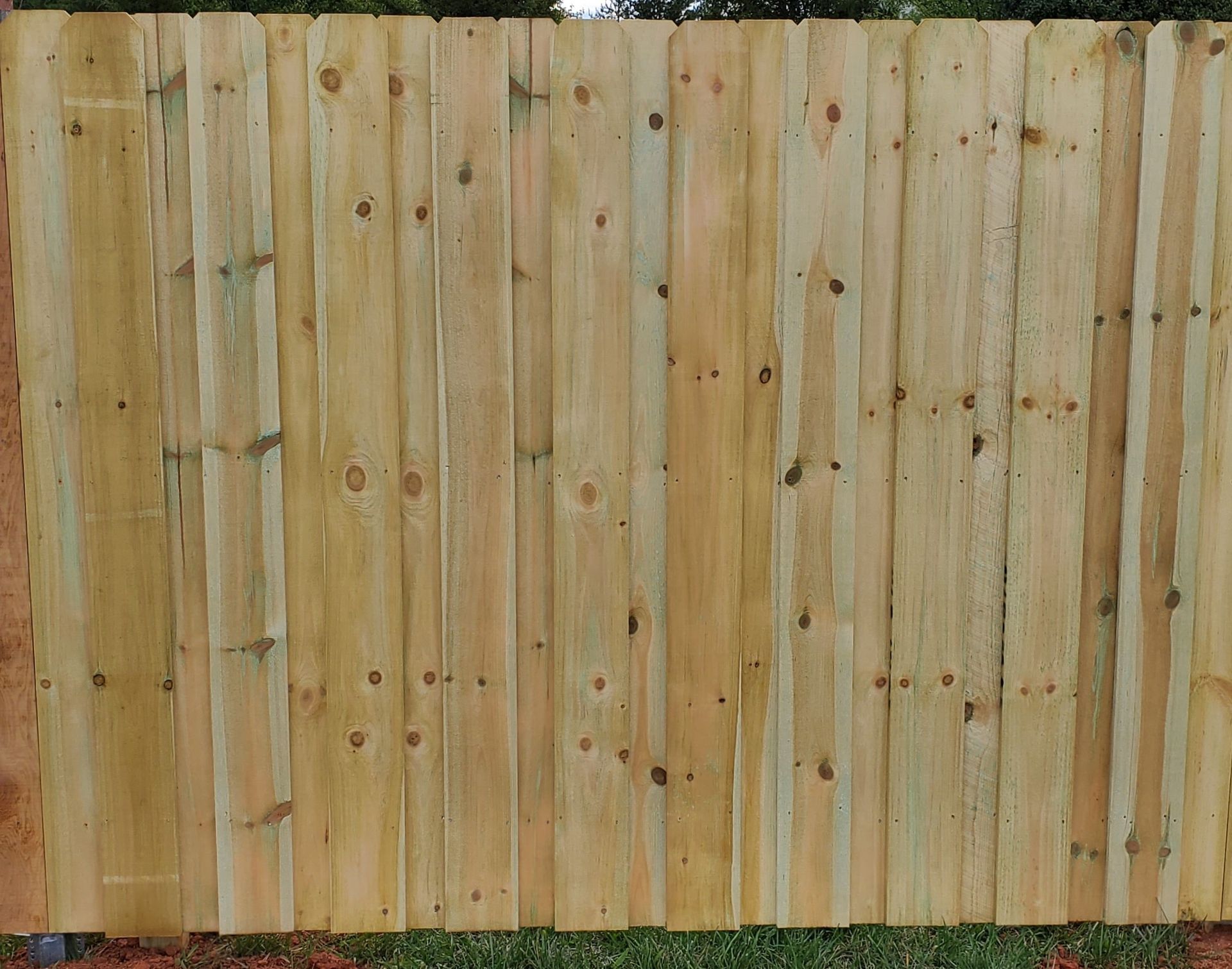 A wooden fence is sitting on top of a lush green field.