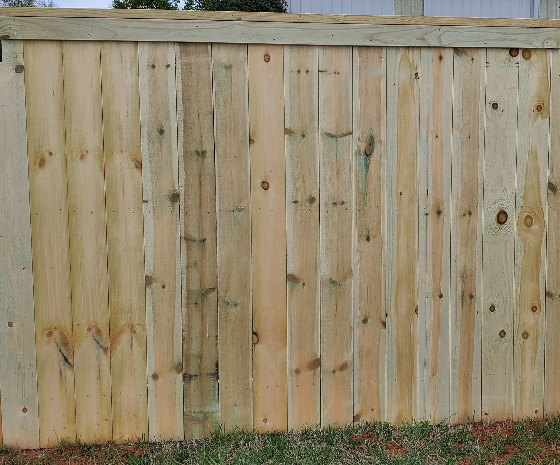 A wooden fence is sitting on top of a lush green field.