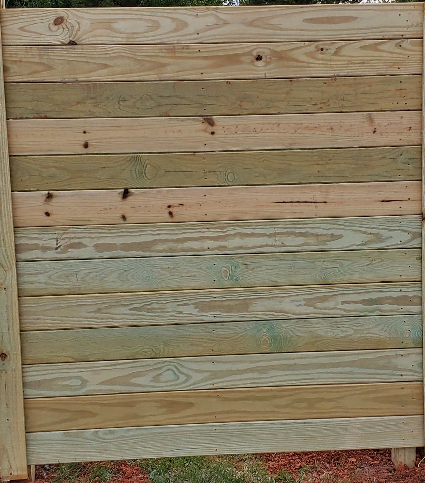 A wooden fence is sitting on top of a dirt field.