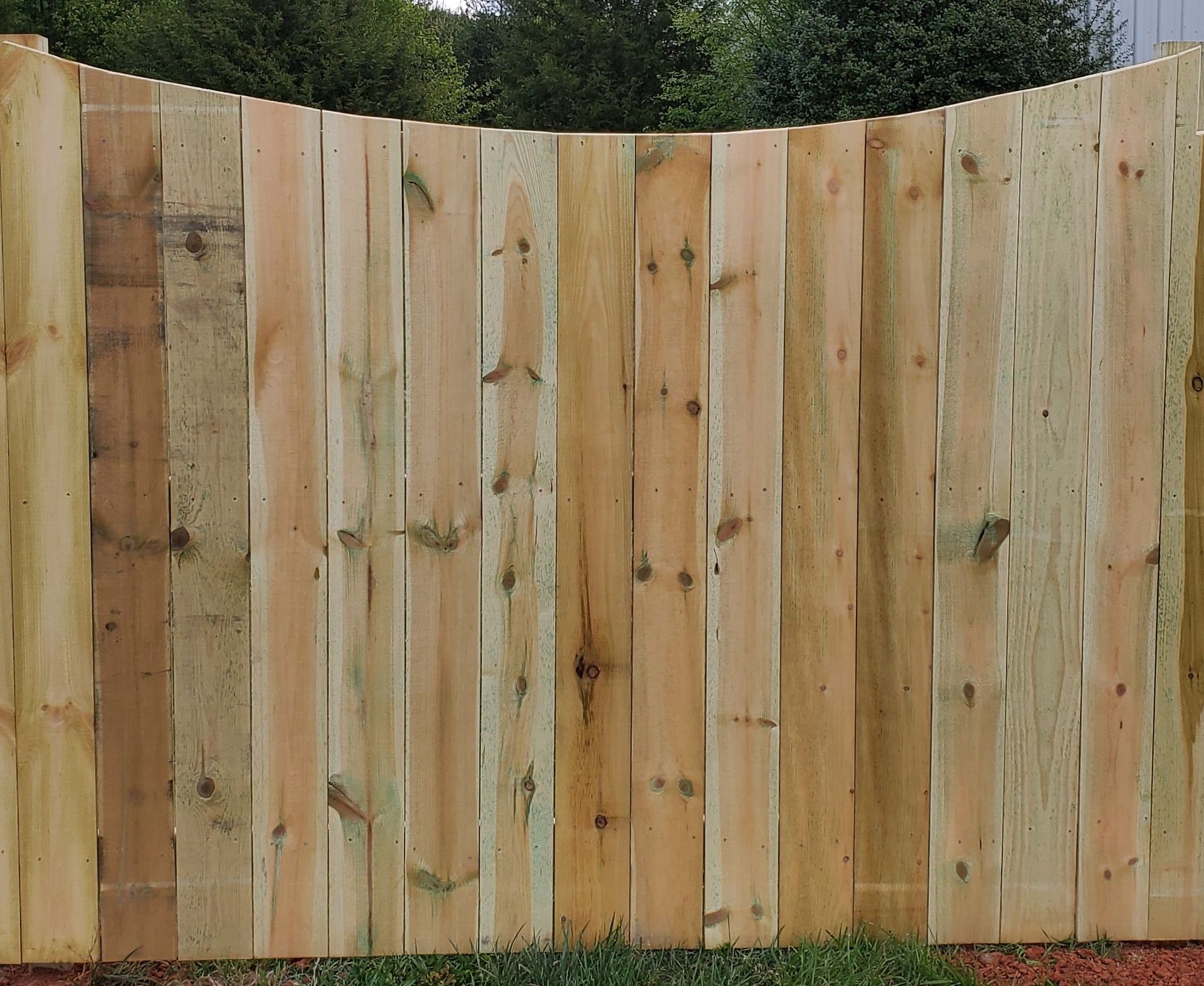 A wooden fence is surrounded by grass and trees