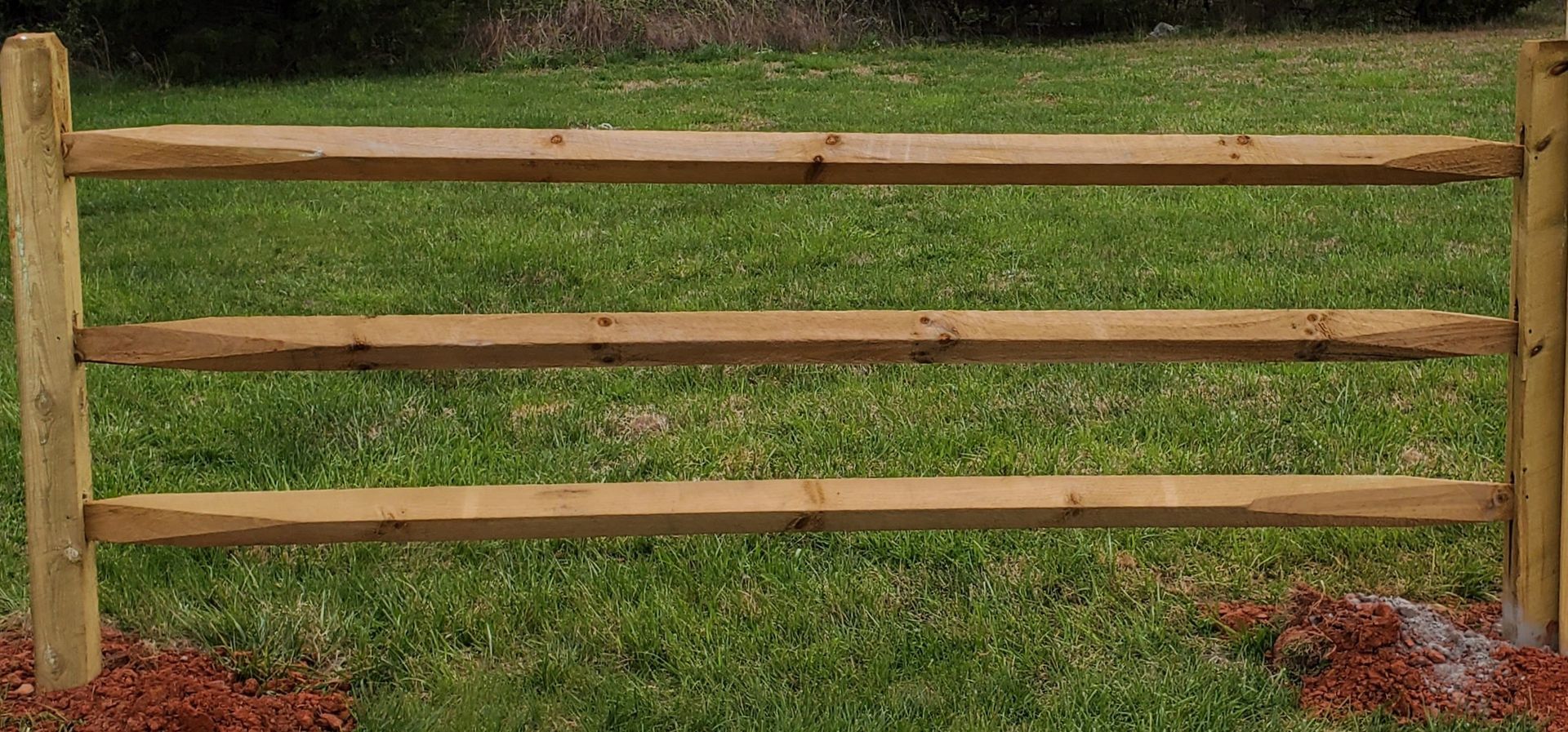 A wooden fence is sitting in the middle of a lush green field.