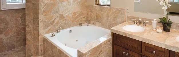 Bathroom with a corner bathtub, sink, and brown marble tile.