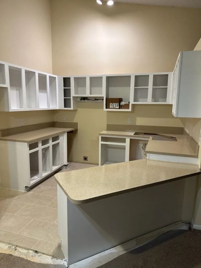 Kitchen under construction with white cabinets, beige counters, and tan walls.