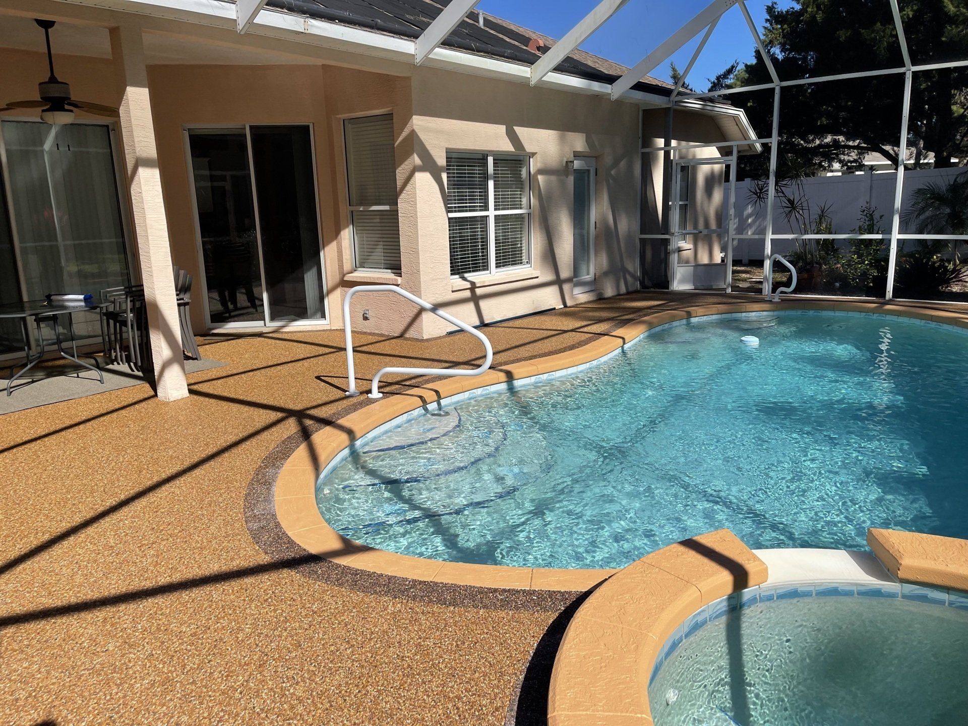 A large swimming pool is surrounded by a screened in area.