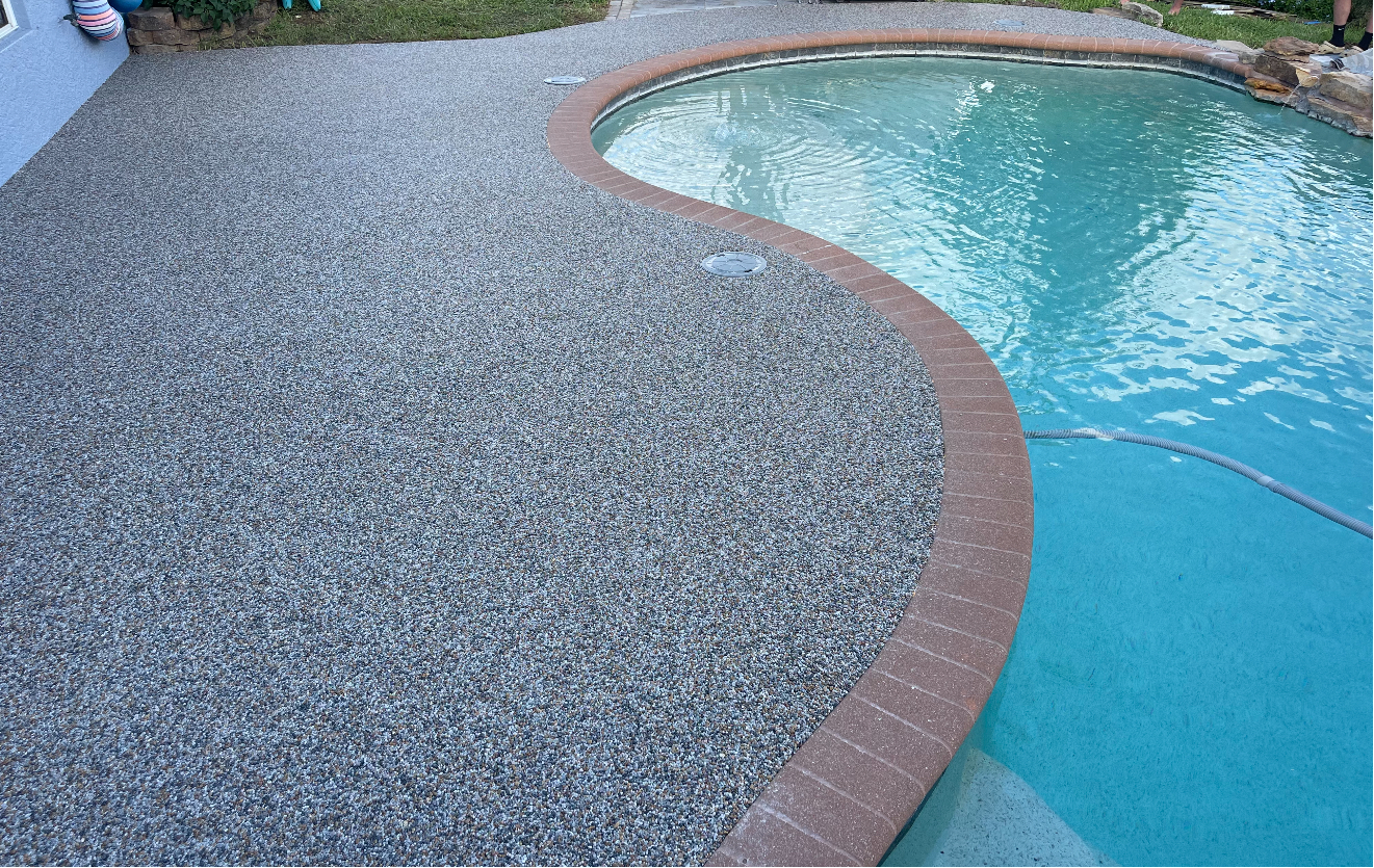 A swimming pool with a brick border and a concrete deck