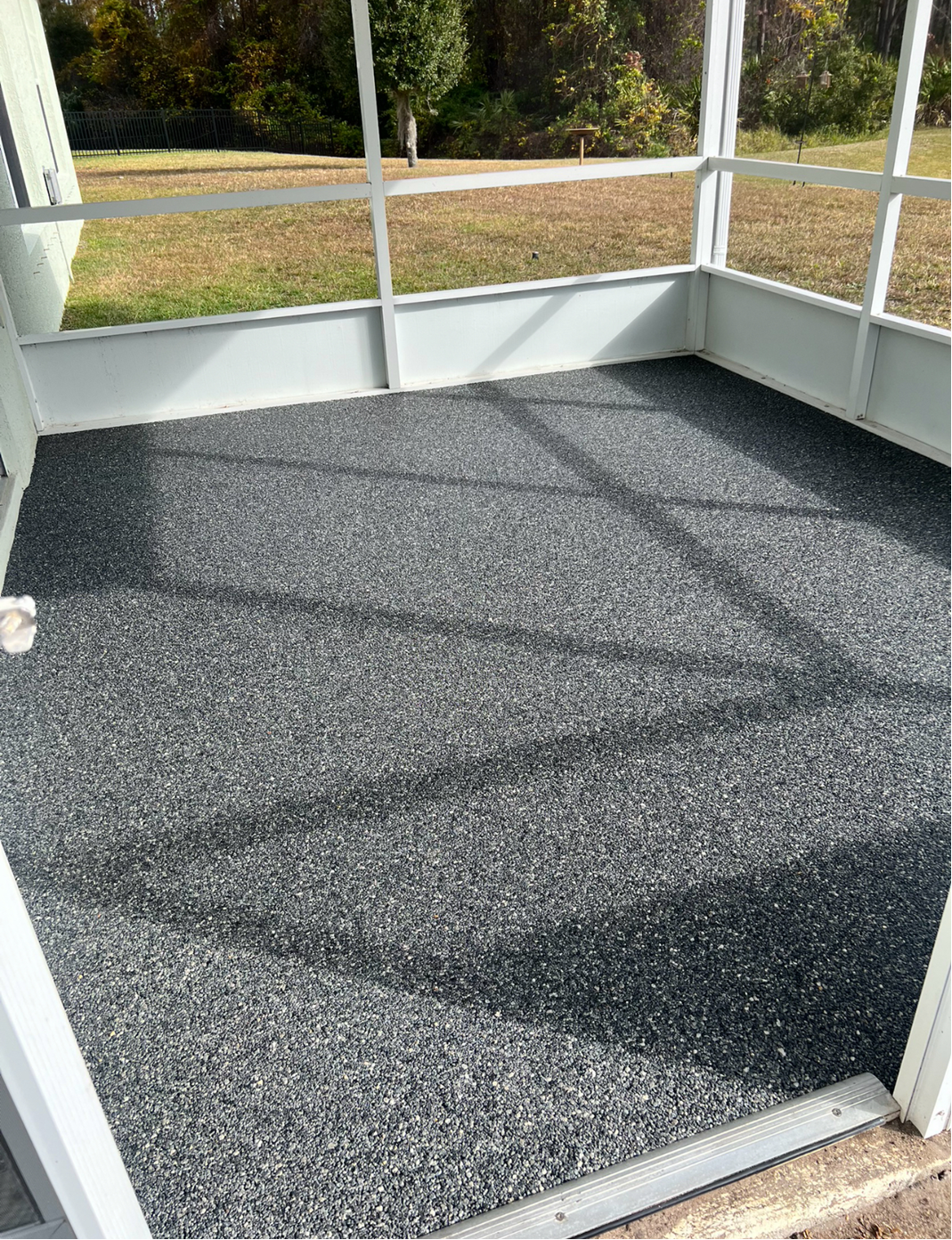 A screened in porch with a gray carpet on the floor.