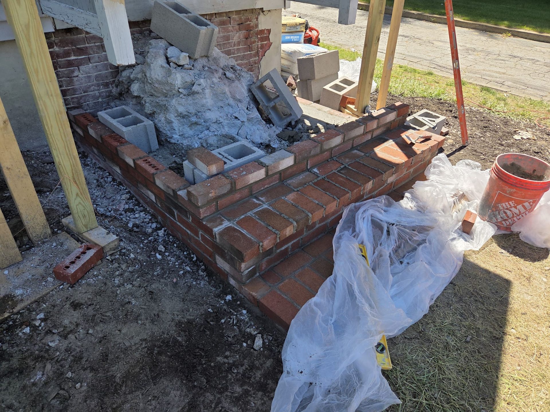 Partially rebuilt brick steps with loose bricks and construction debris beside a house