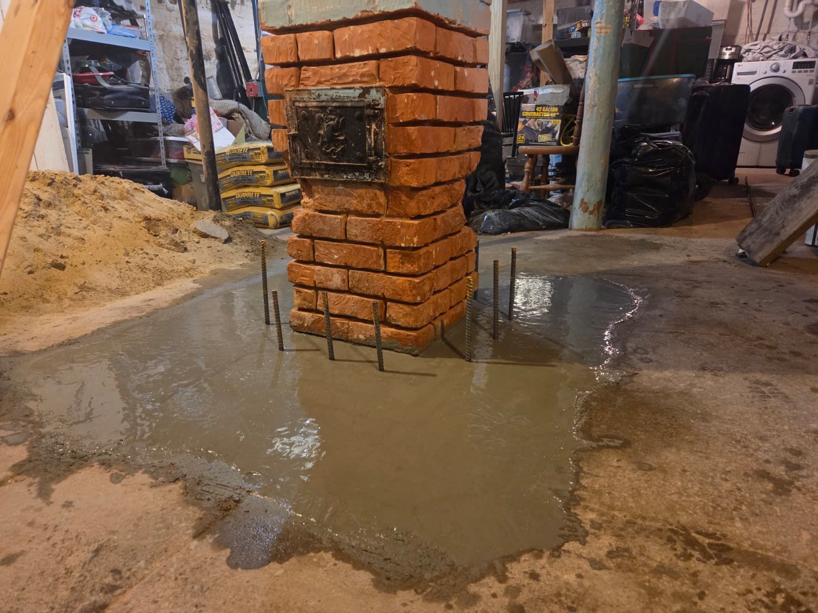 Wet concrete pouring around a brick column in an indoor construction area