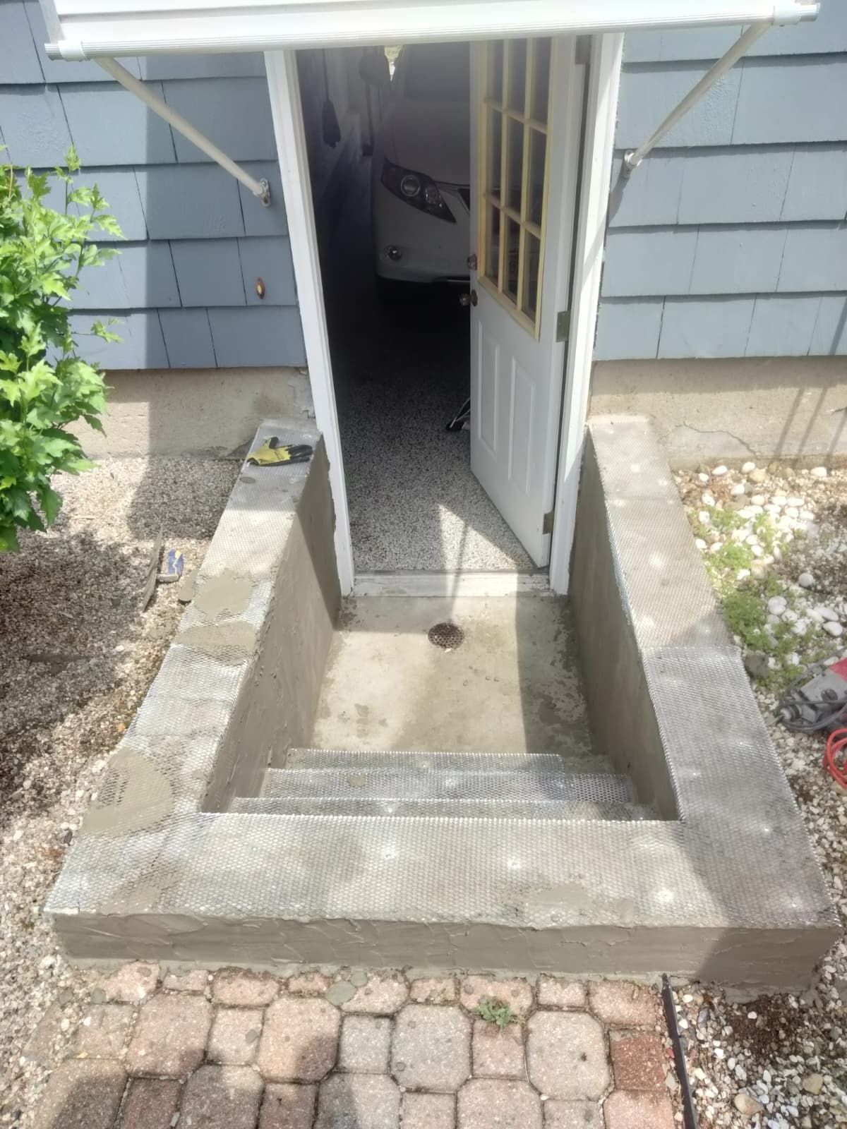 Open doorway with a short concrete ramp and steps leading into a house entrance.