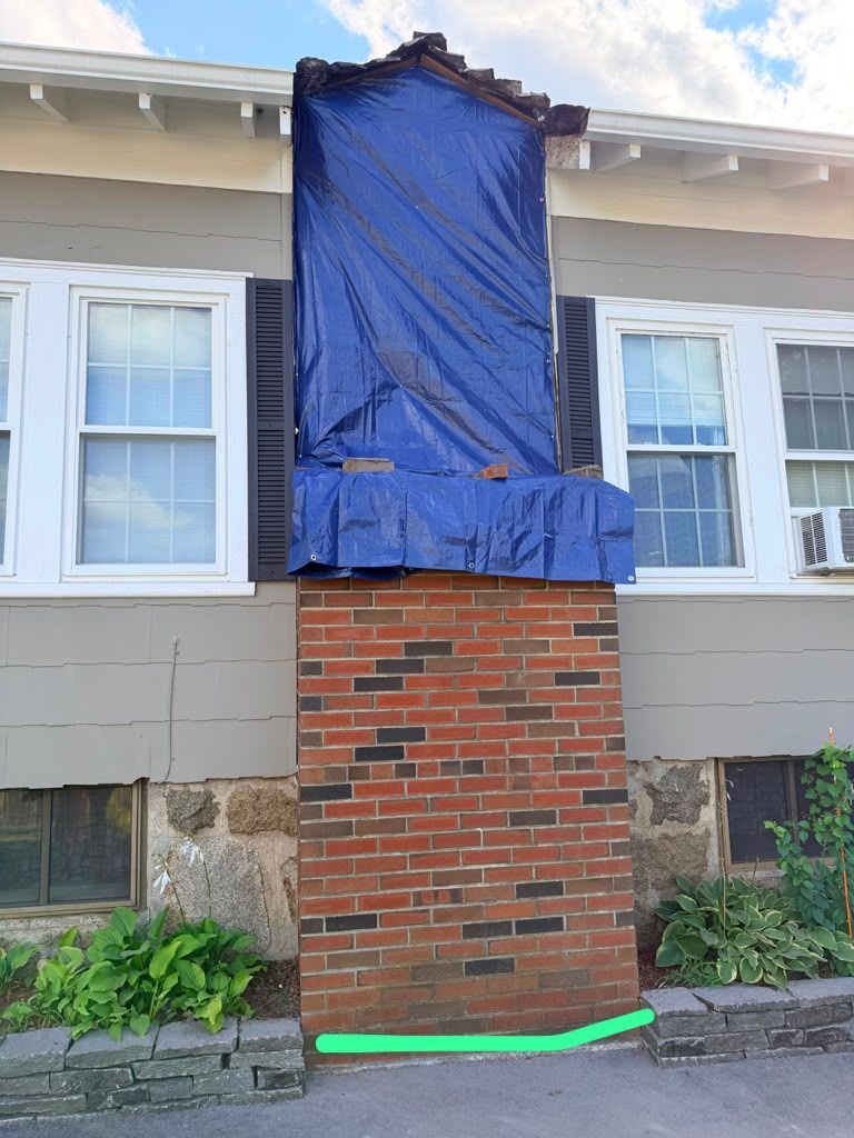 Blue tarp covering the upper part of a brick chimney on a house exterior