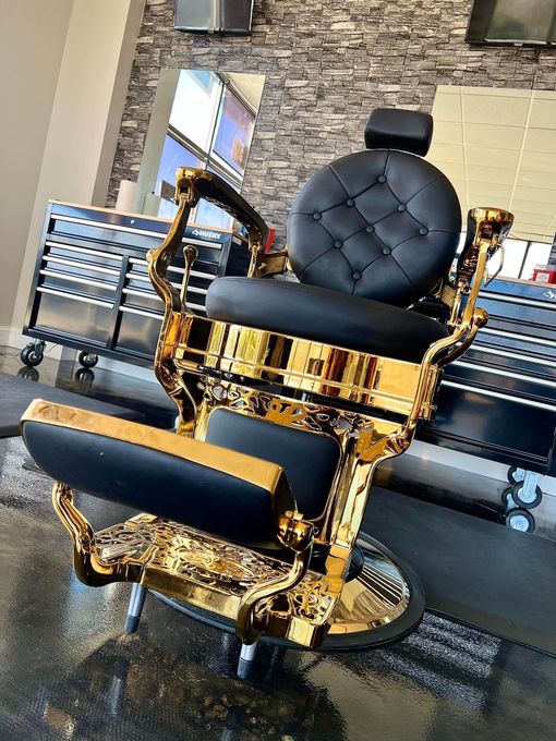 Gold-and-black luxury electric wheelchair with tufted seat and high back, shown indoors on a wet floor.