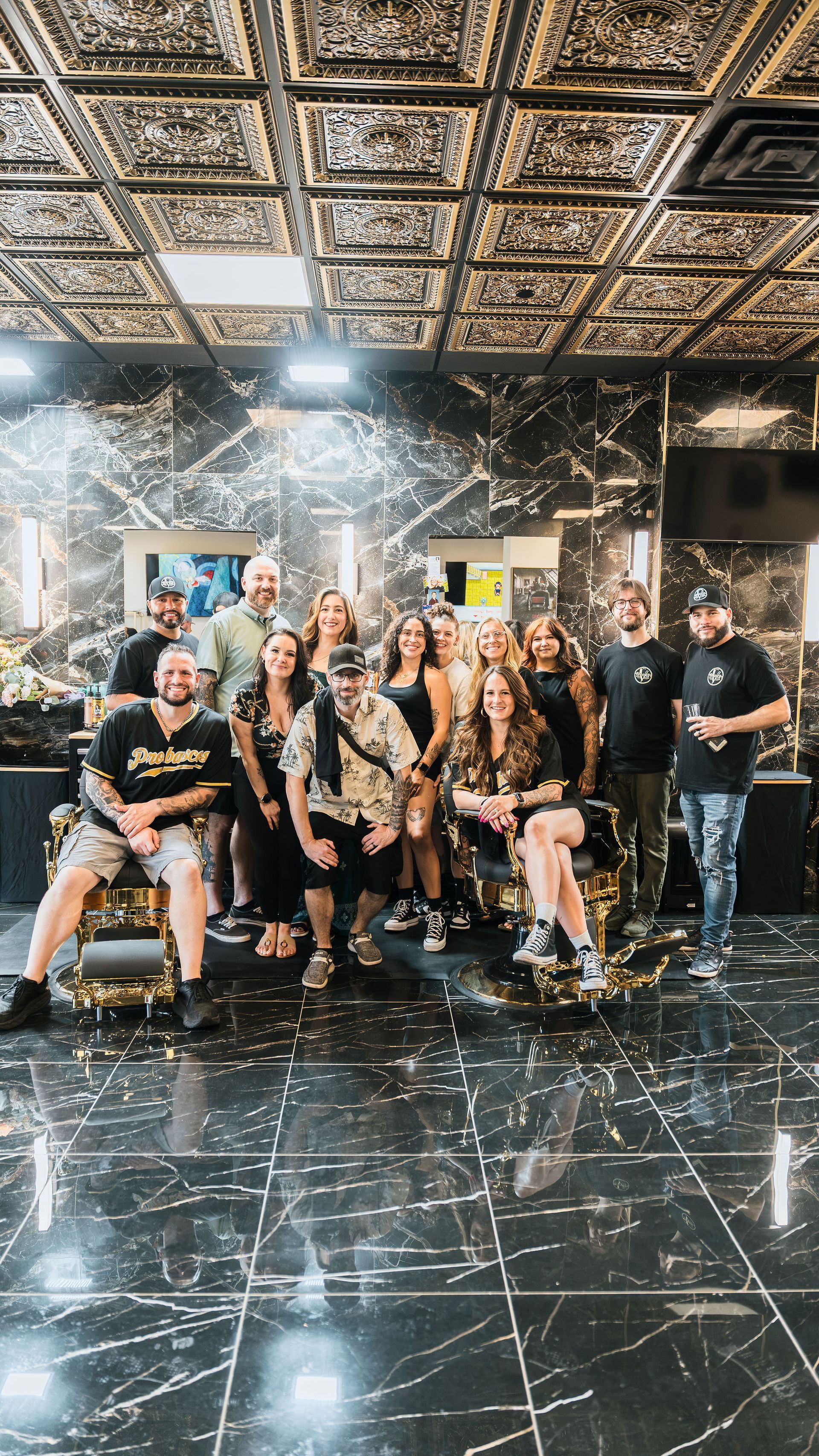 Group posing in a mirrored room with confetti falling and a shiny black floor