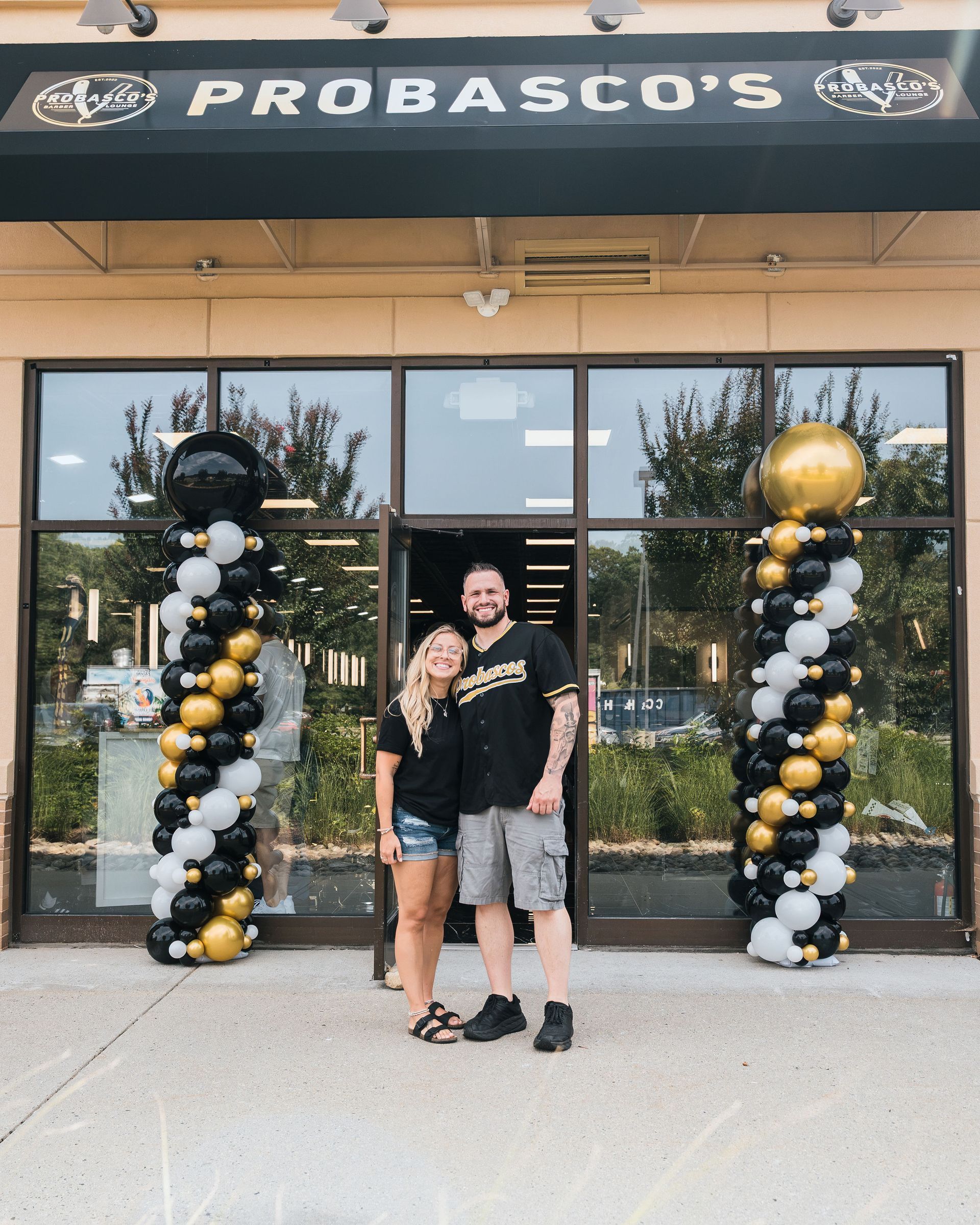Couple standing outside Probasco’s, framed by black, white, and gold balloon columns.