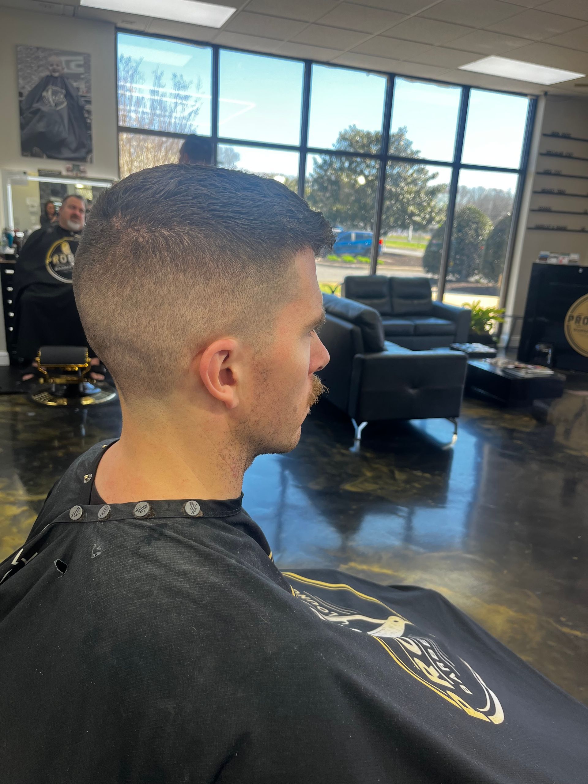 Man in a barber chair with a fresh fade haircut inside a bright barbershop