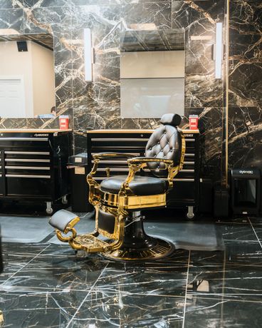 Gold-and-black luxury electric wheelchair with tufted seat and high back, shown indoors on a wet floor.