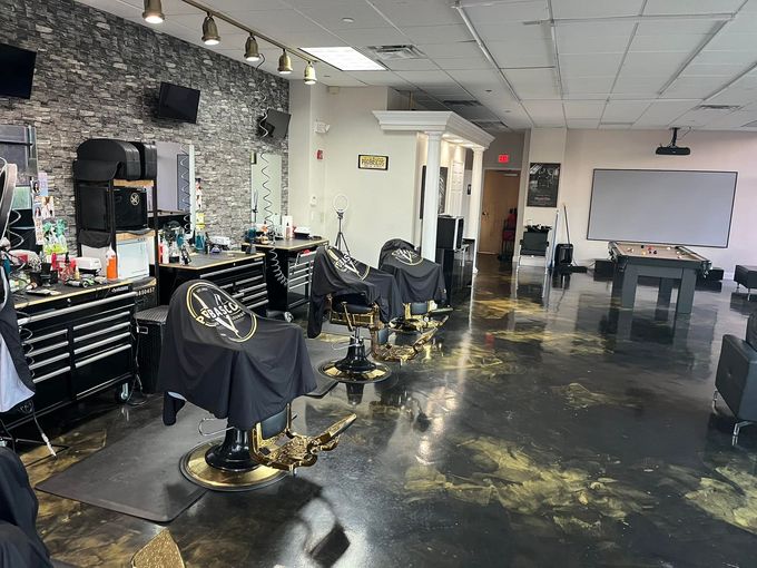 Barbershop interior with several styling chairs, mirrors, tools, and a whiteboard in the background.