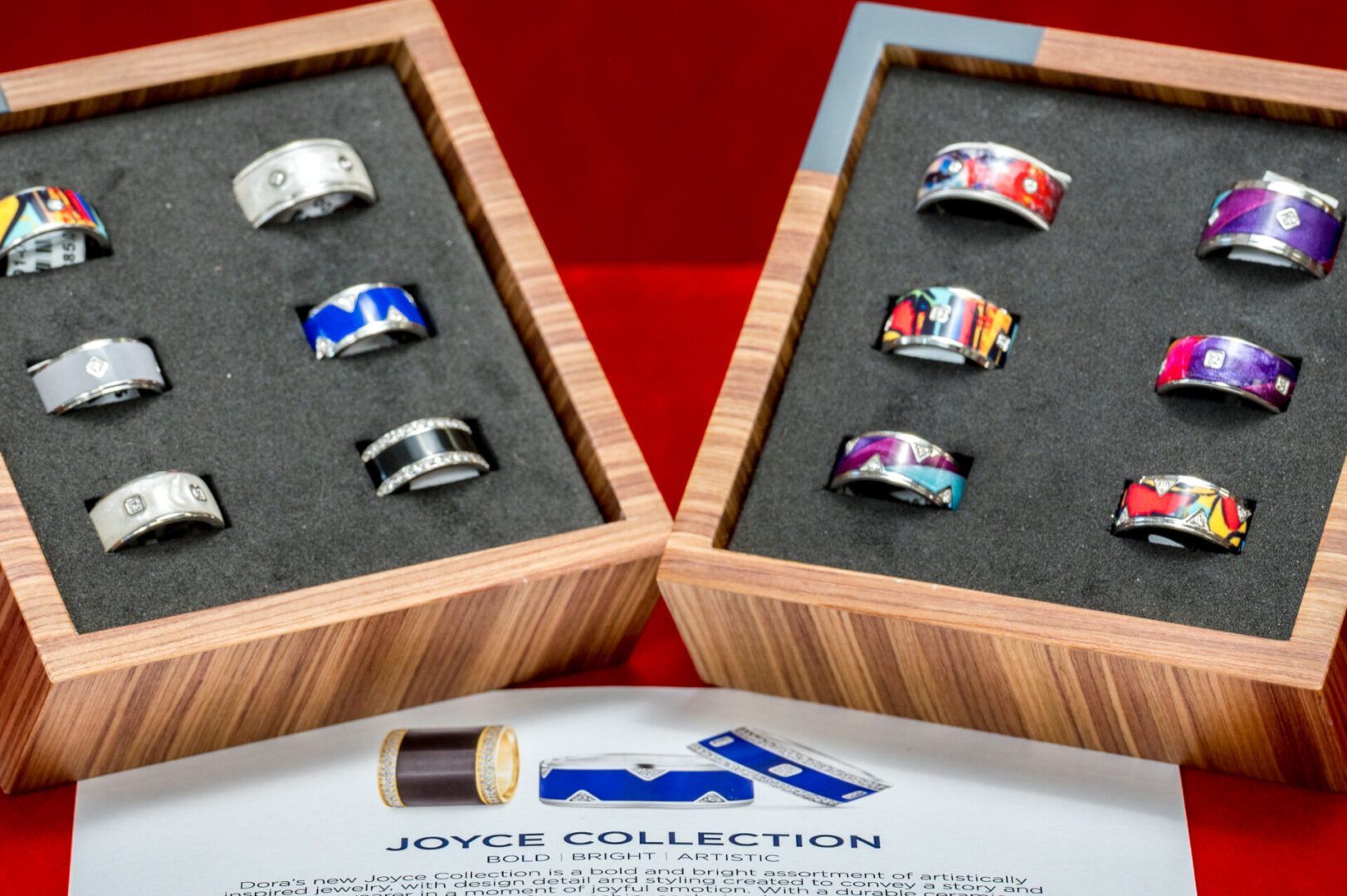 Two wooden display boxes with rings of varying designs and colors, with accompanying paper and examples.