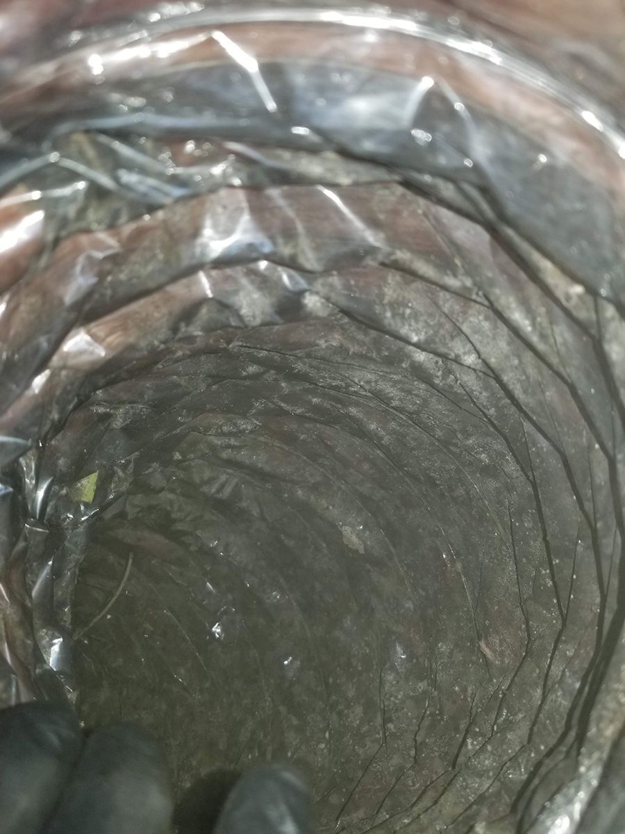 A close up of a dirty air duct covered in plastic.