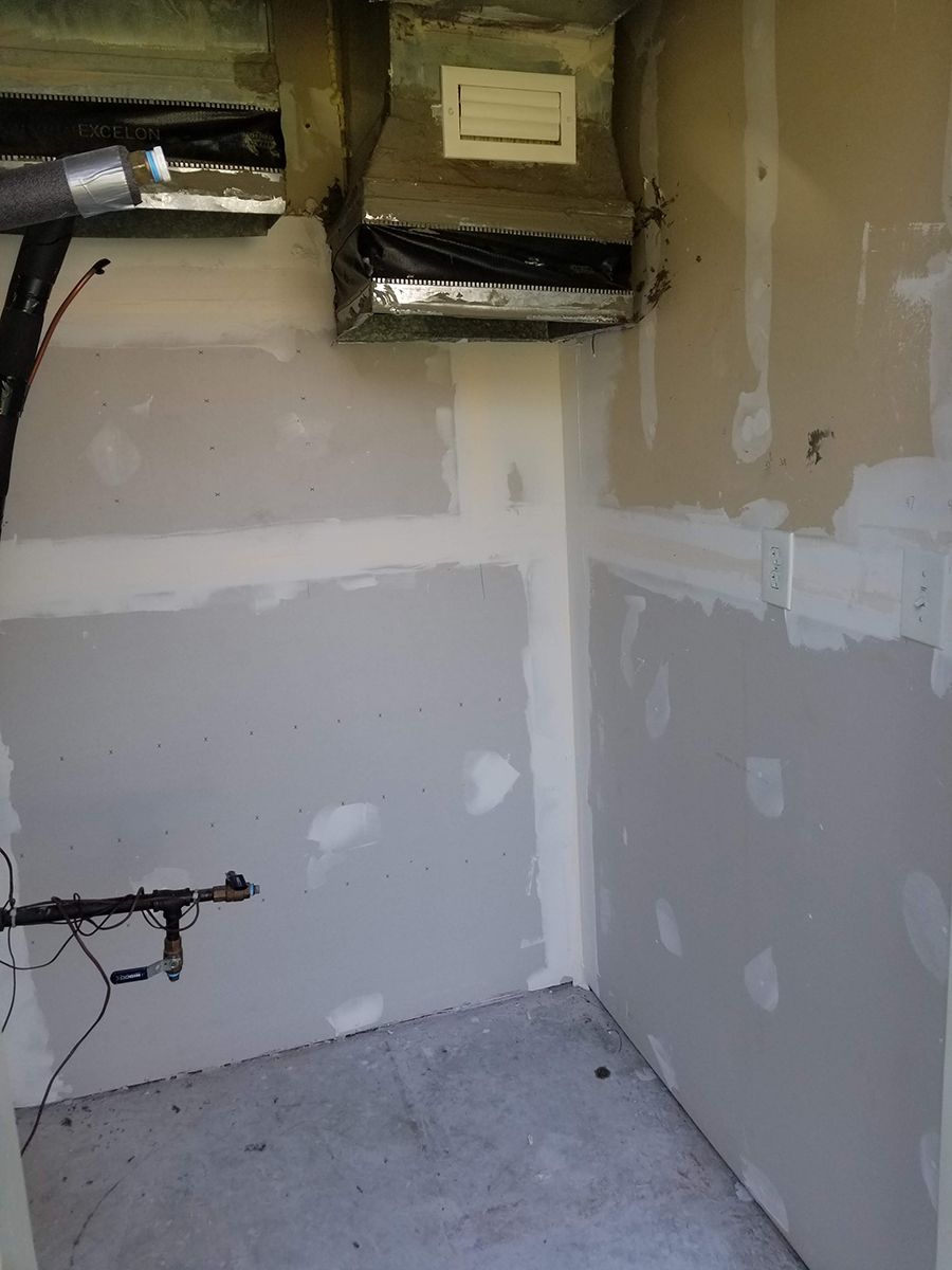 A room with drywall walls and a ceiling fan.