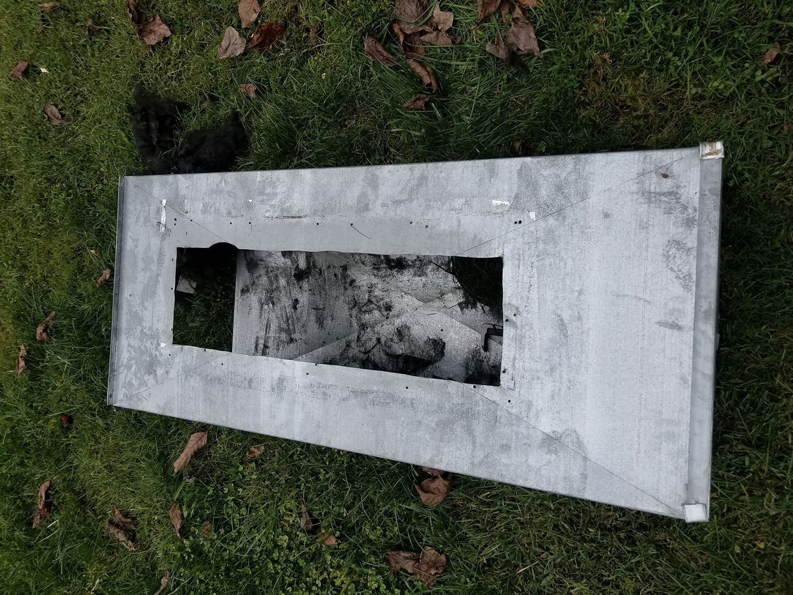 A piece of metal is laying on the grass with a hole in it.