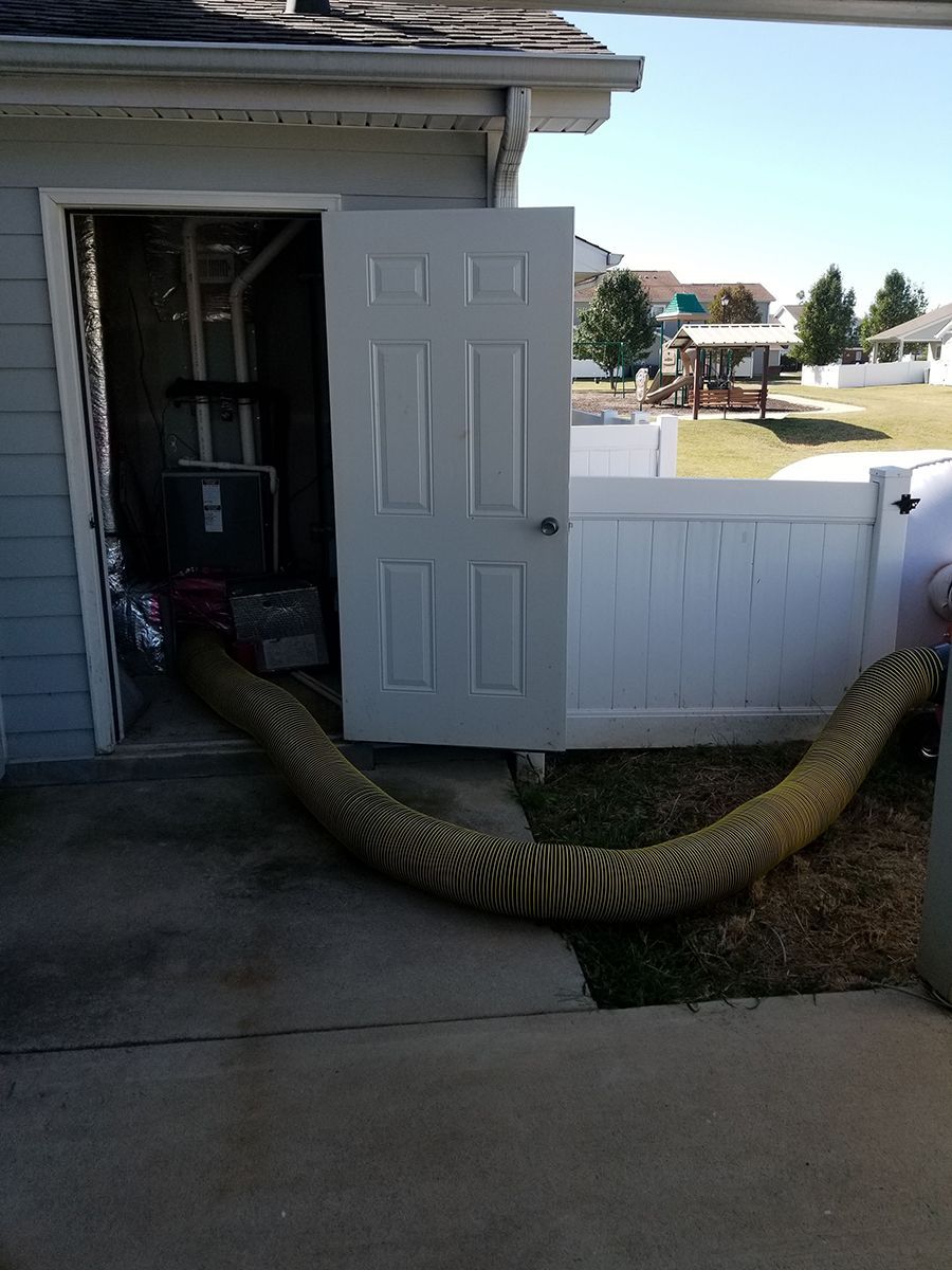 A hose is coming out of the door of a house.