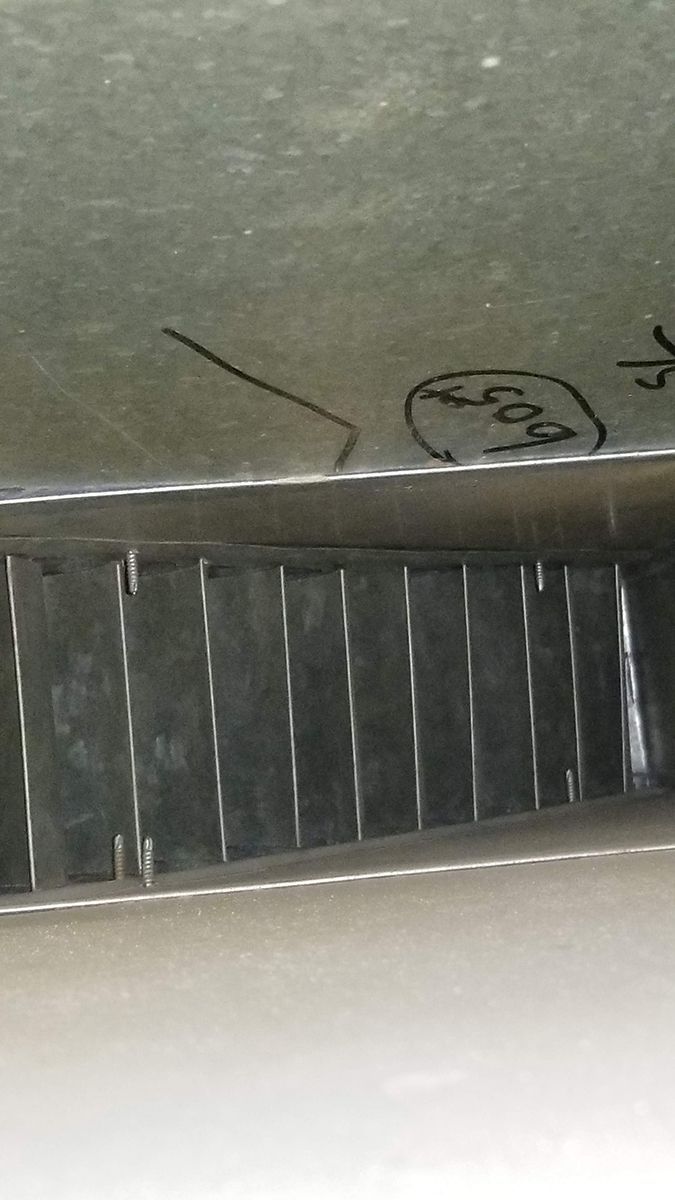 A close up of a metal item with a drawing of a arrow on it
