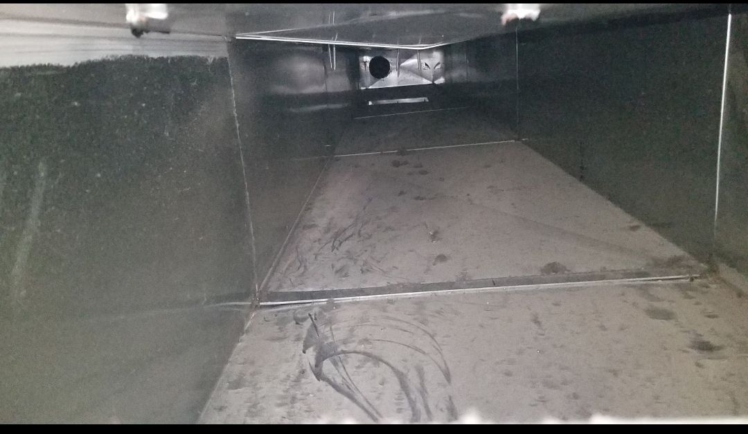 A dirty air duct with a hole in the middle of it.