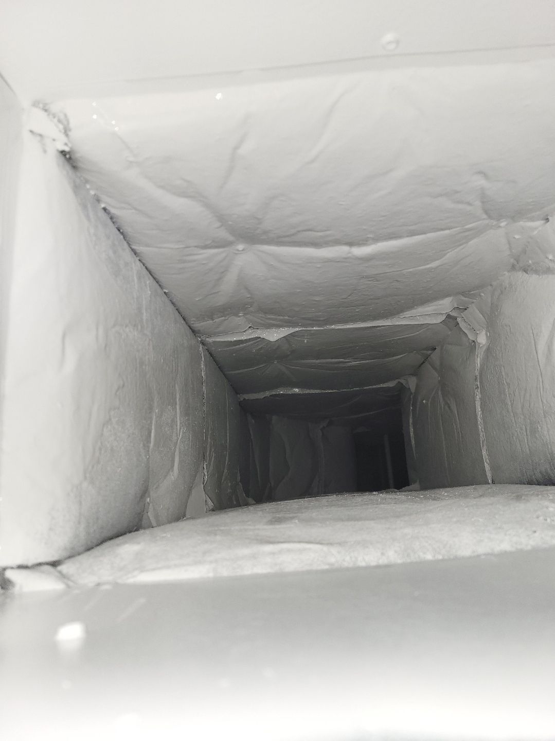 A close up of a white air duct with insulation on it.