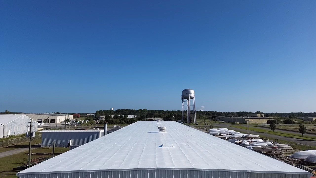 White industrial building rooftop with water tower and clear blue sky.
