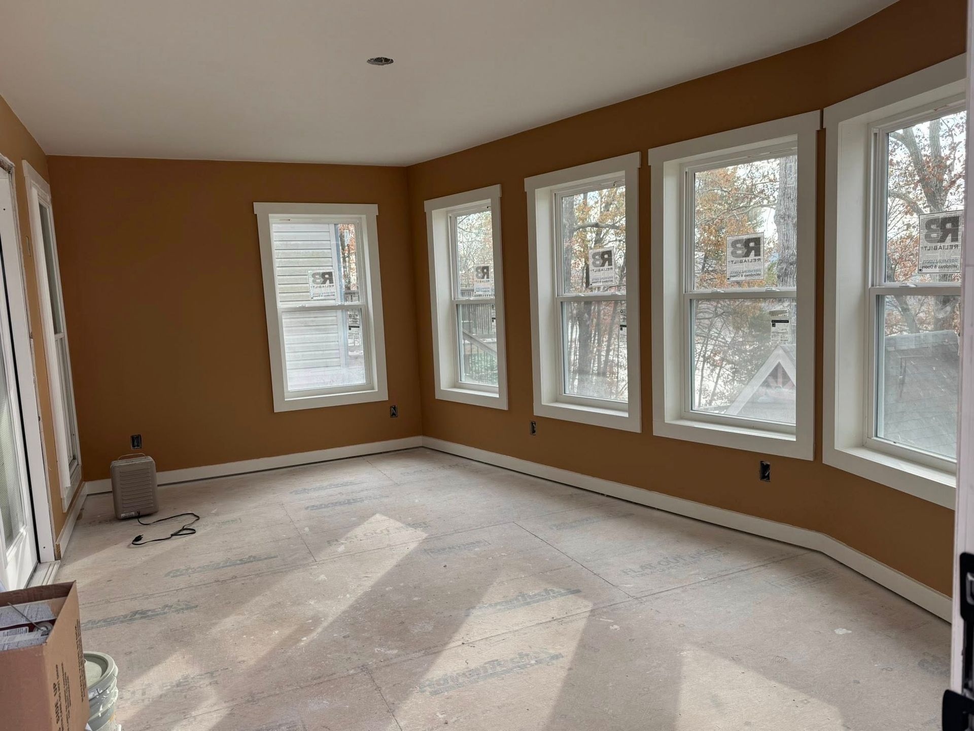 Interior room with tan walls, white trim, multiple windows, and bare concrete floor.