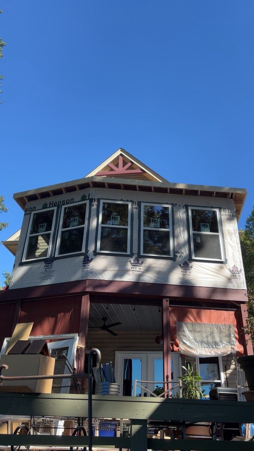 Two-story house with bay windows, red trim, and blue sky.