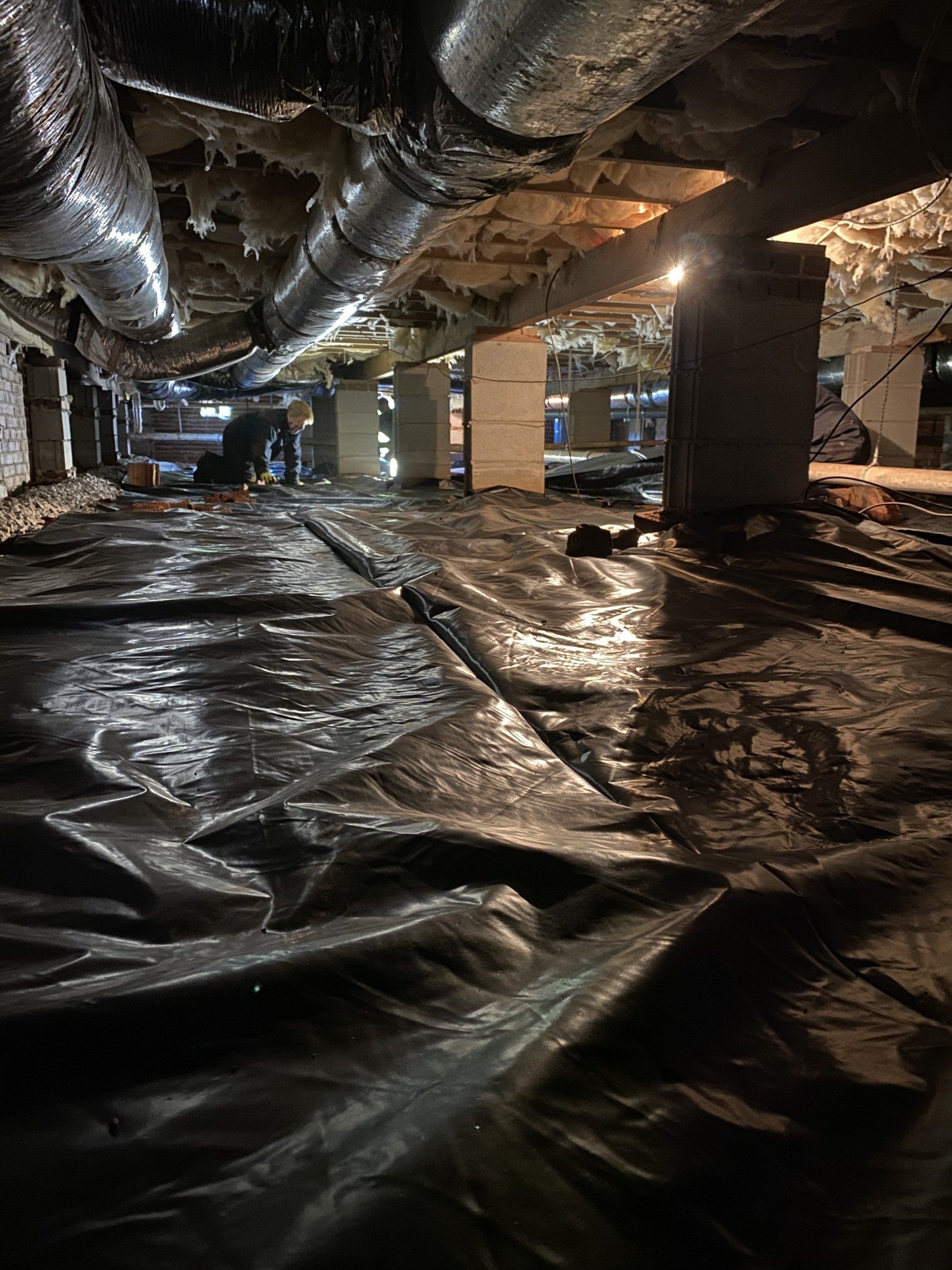 A very dark basement with a lot of pipes coming out of the ceiling.