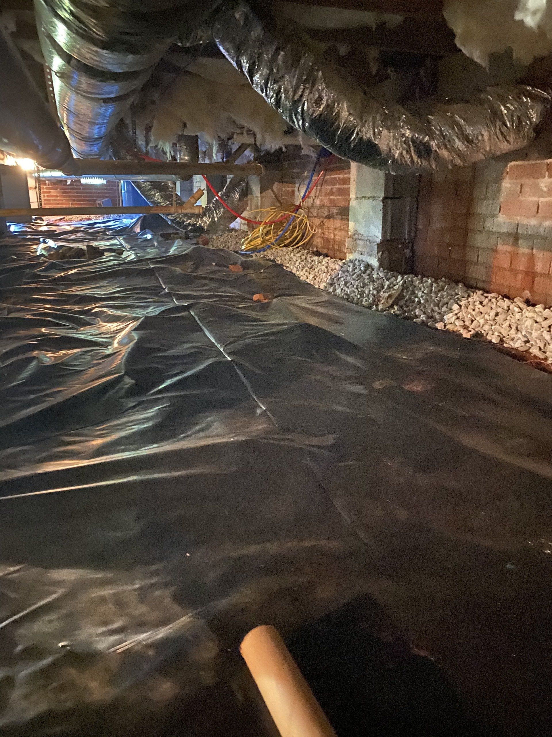 A person is standing in a basement covered in plastic.