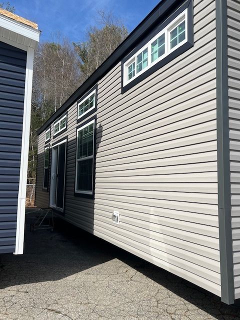 A mobile home with a lot of windows is parked next to a shed.