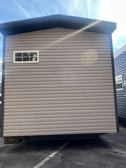A mobile home with a window on the side is parked in a parking lot.