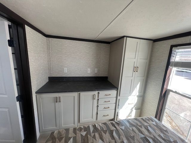 A bedroom with white cabinets and drawers and a window