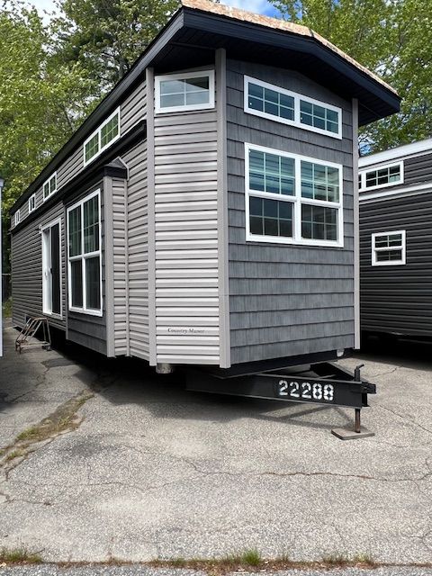 A mobile home with a trailer attached to it is parked on the side of the road.