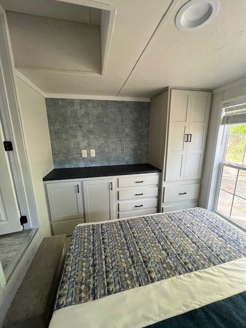 A bedroom with a bed and cabinets and a window
