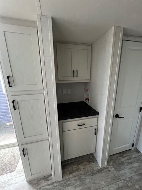 A kitchen with white cabinets and a black counter top.