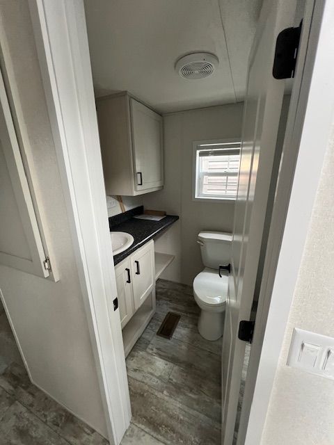 A bathroom with a toilet , sink and window