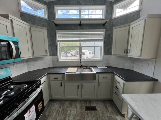 A kitchen with white cabinets and black counter tops