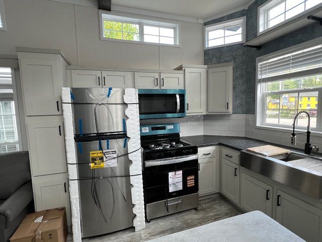 A kitchen with a refrigerator , stove , microwave and sink.