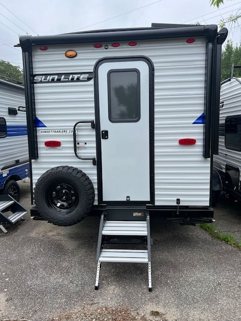 A white trailer with stairs leading up to the door is parked in a parking lot.