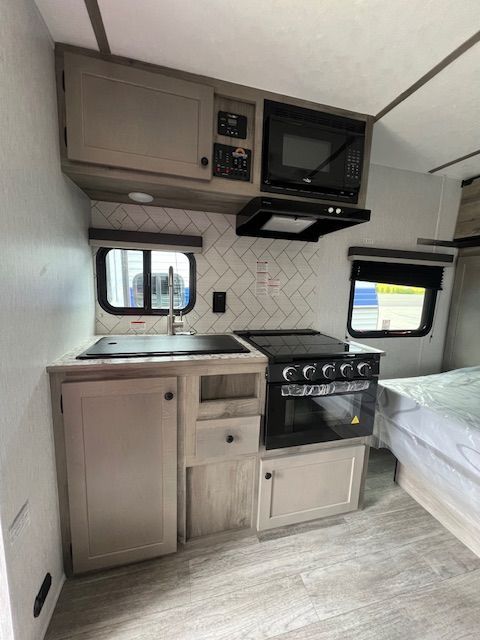 A kitchen in a camper with a stove , sink , and microwave.