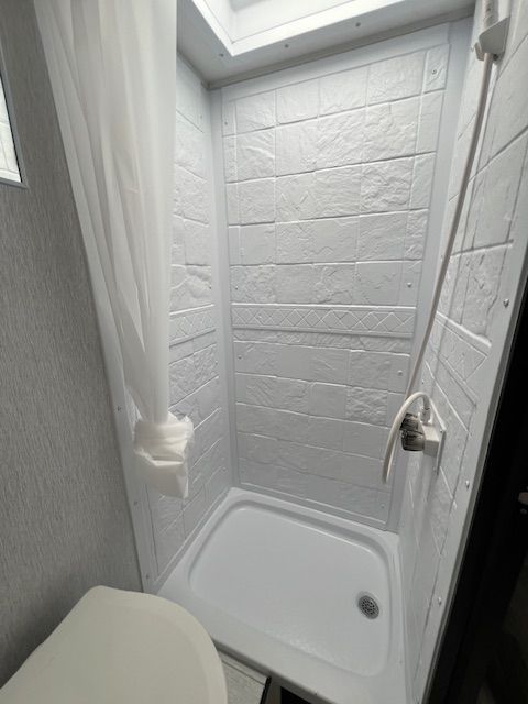 A bathroom with a toilet , shower , and curtain.