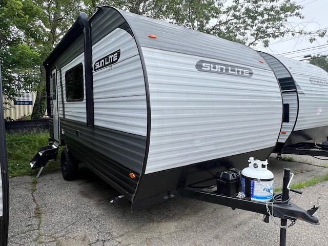A small camper trailer is parked on the side of the road.