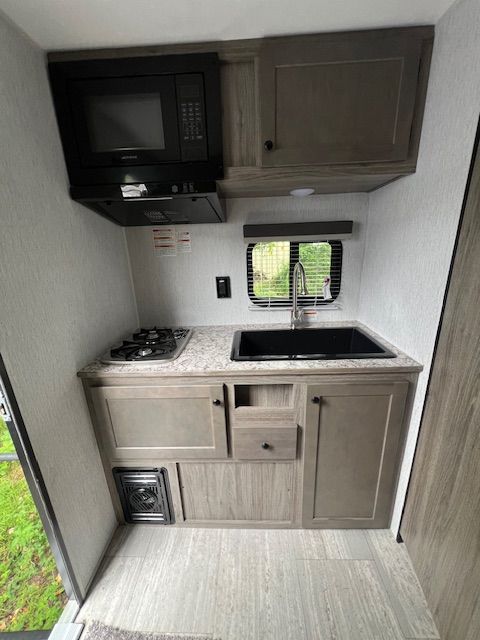A small kitchen with a sink , stove , microwave and cabinets.