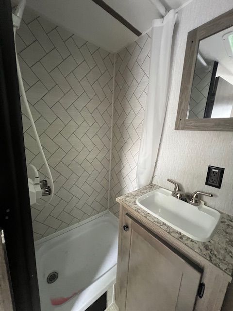 A bathroom with a sink , tub and mirror.